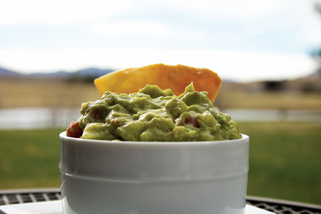 A tortilla chip is dipped into a heaping bowl of super lemon haze Mexican guacamole.