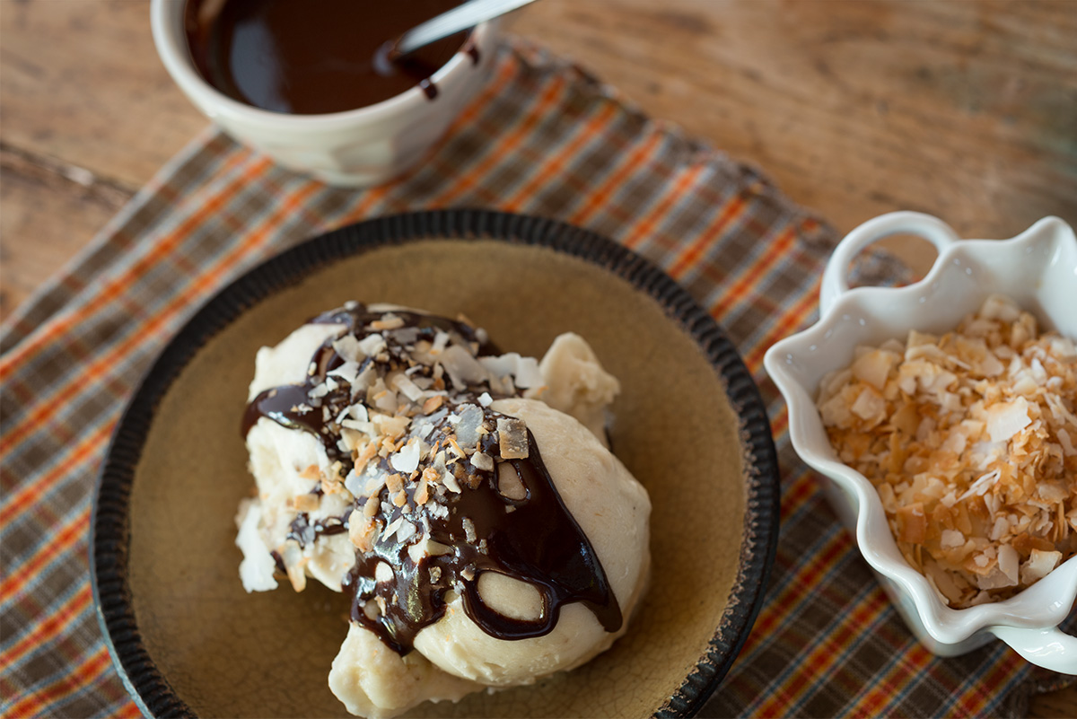 Two scoops of ice cream in a bowl serve as the base of an infused, vegan banana sundae.