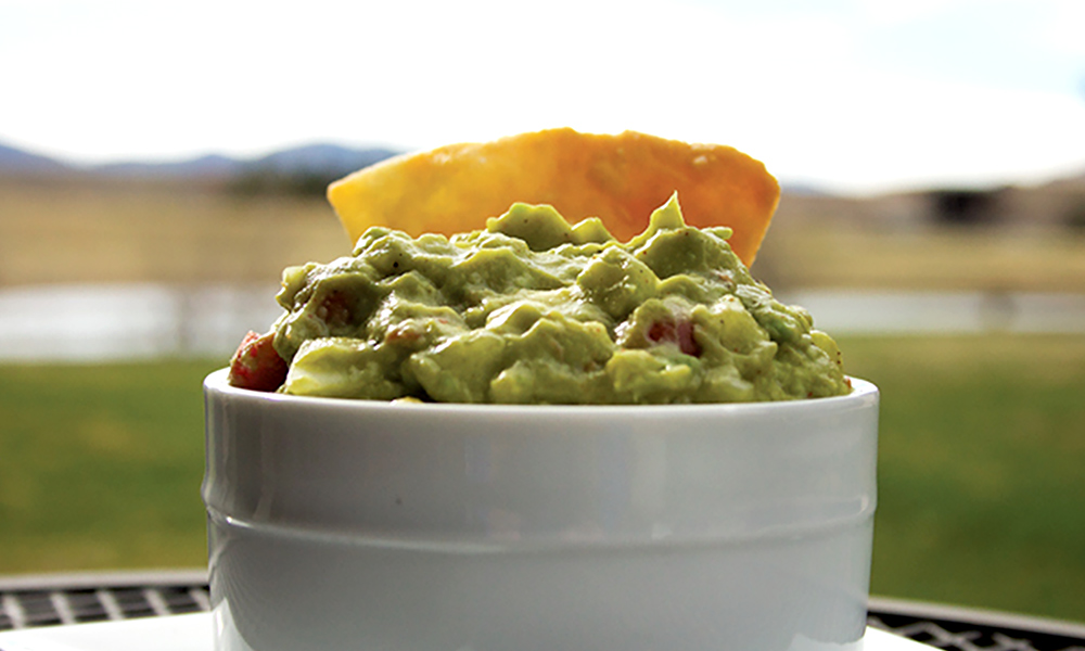 A tortilla chip is dipped into a heaping bowl of super lemon haze Mexican guacamole.